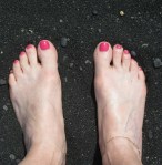 Beautifully manicured toes on the black sand beach of Hawaii.